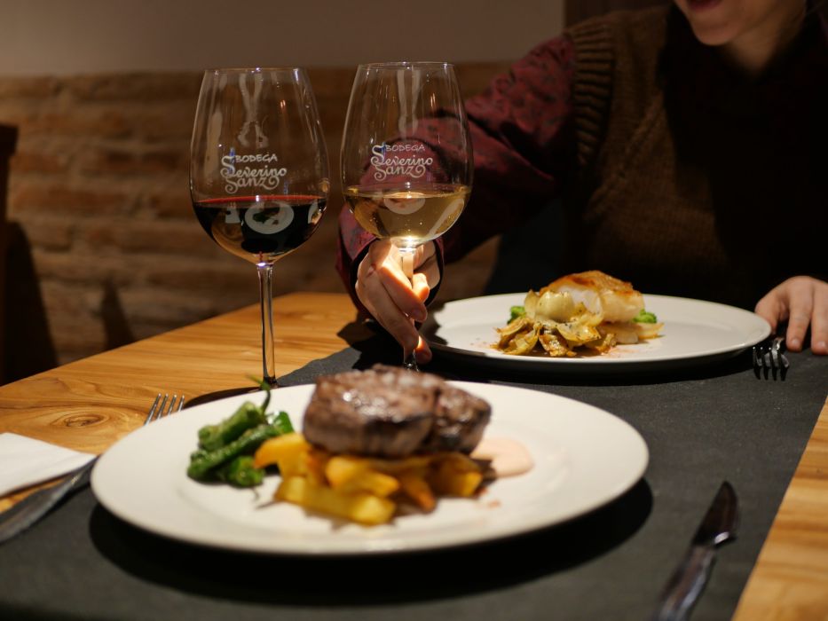 Dos platos con productos gastronómicos acompañan a dos copas de vino de la Bodega Severino Sanz